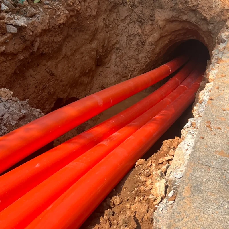 Underground trenchless installation of red MPP power pipes for cable protection
